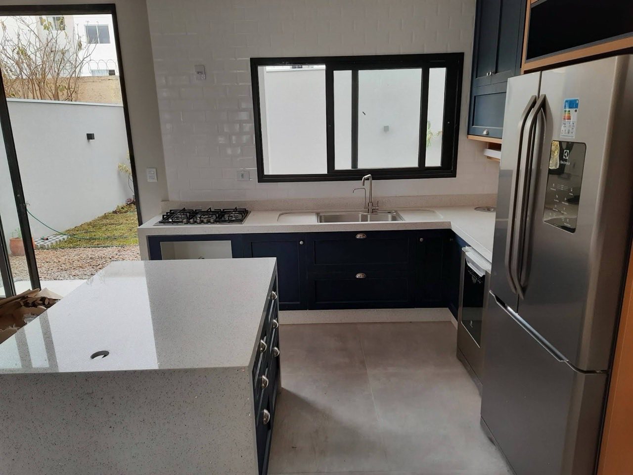 Cozinha planejada completa com armários azul-marinho e bancada em quartzo claro
